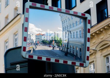 A closeup of a convex traffic mirror with a reflection of the street with buildings in Bratislava, Slovakia Stock Photo