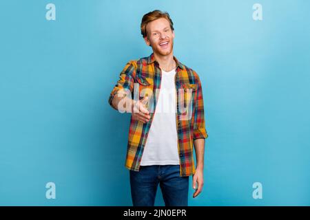 Photo of handsome positive good mood redhead guy dressed checkered shirt give hand welcome you isolated on blue color background Stock Photo
