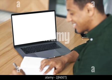 African American young student or freelancer man working remotely takes notes communicates online using video call Stock Photo