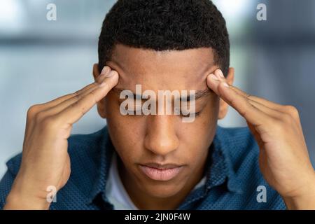 Portrait of tired stressed man having headache feeling sick Male holding his temples suffering from migraine Stock Photo