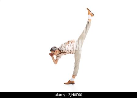 Portrait of stylish man in retro outfit, standing on twine and attentively looking, posing isolated over white studio background Stock Photo