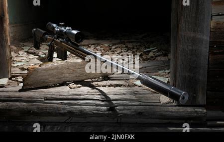 Bolt action sniper rifle with a silencer in a building that is abandoned Stock Photo