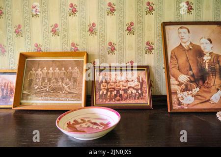 Family, military and sports team old photographs on a bookcase. In a recreation of a typical, generic worker's house, home from 1927 at Blaenavon Iron Stock Photo