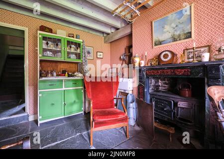 The living area with wrought iron cook stove in the fireplace, an alcove with kitchen sink and a green dish cabinet. In a recreation of a typical, gen Stock Photo