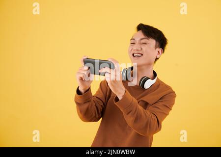 Happy excited young man playing videogame on smartphone Stock Photo