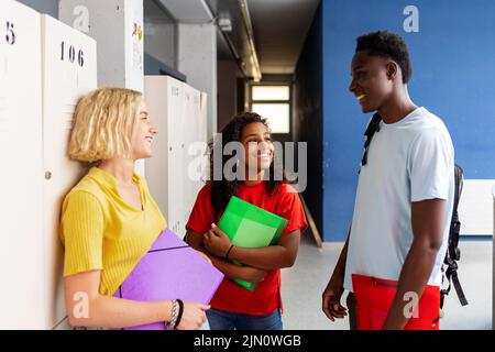 Multiracial group of student friends talking at high school corridor Stock Photo