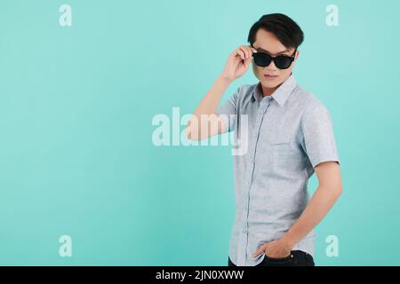 Cool stylish young man taking off sunglasses and looking at camera Stock Photo