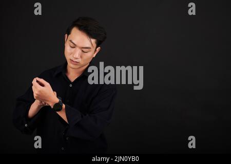 Serious young man wearing smartwatch, isolated on black Stock Photo