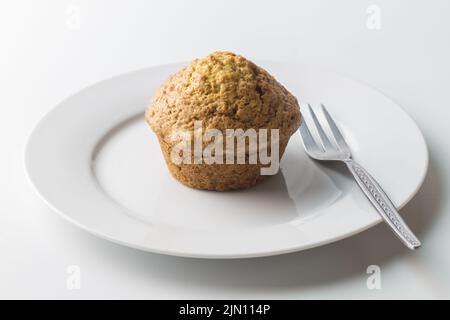 Muffin on white plate with cake fork Stock Photo