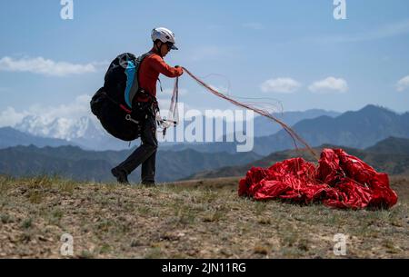 (220808) -- XINJIANG, Aug. 8, 2022 (Xinhua) -- Chen Ruifeng practices paragliding in southern suburb of Urumqi, northwest China's Xinjiang Uygur Autonomous Region, May 24, 2022. Born in Xinjiang, 52-year-old Chen Ruifeng is a paragliding amateur. He says he feels like having his own wings when the paraglider opens. In 2016, Chen Ruifeng started to practice paragliding. Later on, he joined a local club and received his flying certificate after training. As an outdoor enthusiast, he also engages himself in trail running, mountaineering and ice climbing. In his opinions, the unique terrain of Xin Stock Photo