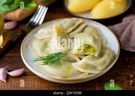 Ukrainian or polish dumplings, pierogi stuffed with potato and spinach mash served with olive oil, closeup view Stock Photo