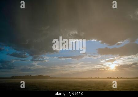 July 8, 2022.  7:46 pm. Rain squall, blue sky, and sun, all together.  View from Barnes Island.  Casco Bay, Maine.  Rain Storm Series. Stock Photo