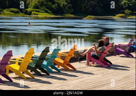 colorful Adirondack chairs along the Kennebec river in Hallowell Maine Stock Photo