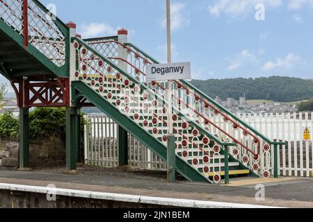 Deganwy  north Wales united kingdom 01 August 2022  Deganwy  railway station ornate and colourful bridge, conway castle in background Stock Photo