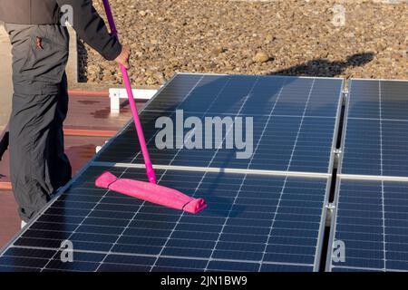 Close up view of face less worker cleaning the solar panels farm with working outfit Stock Photo
