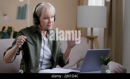Portrait mature female in headset teacher online mentor business trainer psychologist talk in headset senior business woman talking laptop webcam lead Stock Photo
