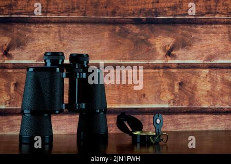 Compass and binoculars on a polished wooden shelf Stock Photo