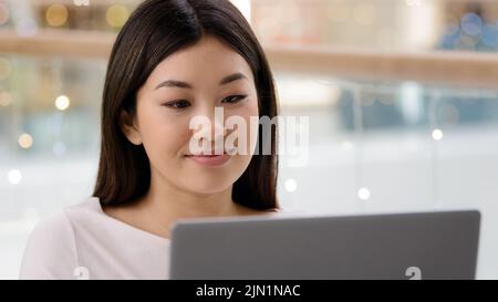 Portrait asian female face looking at laptop satisfied girl woman freelancer boss worker manager businesswoman typing computer using shopping app Stock Photo