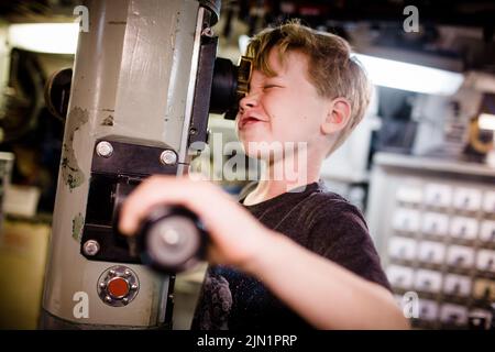 Eight Year Old Boy Looking Through Submarine Periscope in San Diego Stock Photo