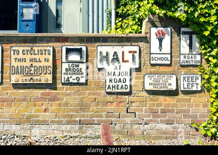 collection of vintage cast metal road signs  on brick wall at Beamish County Durham Stock Photo