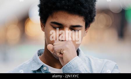 Male portrait sad african american man sick guy indoors coughing covering mouth with hand sore throat problems with breathing covid symptoms asthma Stock Photo