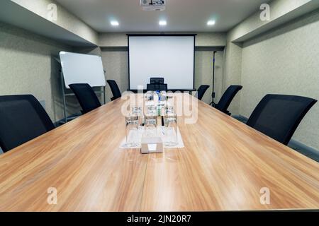Conference room for business meetings a large table in the middle of the room around comfortable chairs, there is water on the table Stock Photo