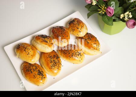 freshly baked assorted rolls with a stuffing in a white plate on the table. Stock Photo