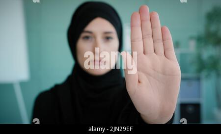 Portrait serious frustrated angry Arabian Muslim Islamic girl in black hijab upset woman looking at camera holding hand in front forbidden gesture Stock Photo