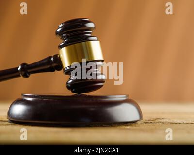 Close-up. On a wooden table is a judge's gavel on a beige background. Minimalism. Judgment and justice, auction. There are no people in the photo. The Stock Photo