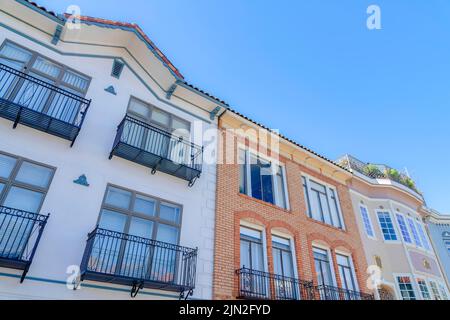 Low angle view of adjacent houses with window railings in San Francisco, California. There is a building in the middle with bricks beside the house on Stock Photo