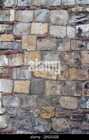 Full frame texture background of an old medieval European gray color stone wall with a rugged appearance Stock Photo