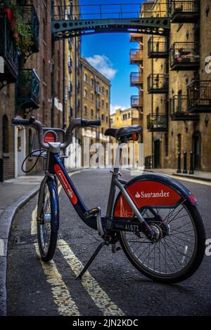 Santander Bike parking in the middle of Shad Thames, one of the oldest streets of London, with warehouses in the background; Sustainable Bike sharing Stock Photo