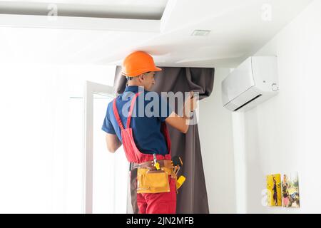 man screwing window curtain rod support on the wall Stock Photo