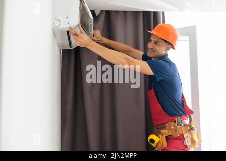 technician service removing air filter of the air conditioner for cleaning. Stock Photo