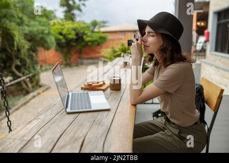 Young female traveler making photo while sitting in cafe outdoors Stock Photo