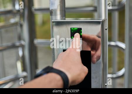 Hand pressing a fingerprint reader to open a security door Stock Photo