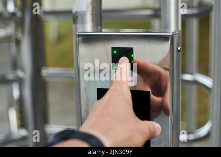 Hand pressing a fingerprint reader to open a security door Stock Photo