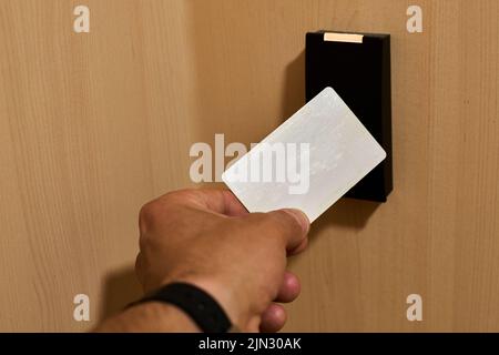 Hand approaching a card to an rfid reader to open a security door Stock Photo