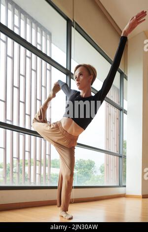 Professional female dancer stretching legs to warm up before performance Stock Photo