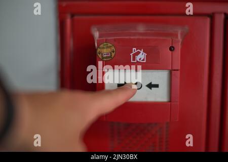 Hand pressing on the trigger of a fire alarm Stock Photo