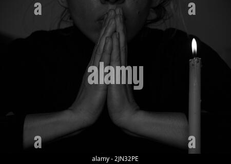 A young Ukrainian girl prays near a candle for Ukraine in Ukraine, a girl poured candles in the dark close-up Stock Photo