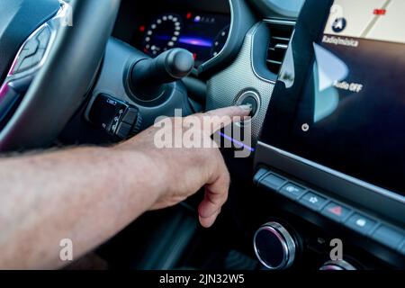 Close up of finger on starting the car engine using a special start / stop button built into the console in luxury car. Stock Photo