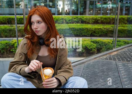 Cool teenage hipster girl eating ice cream on big city urban street. Stock Photo