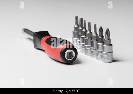 Screwdriver with attachments on the table on a white background. A set of small nozzles. A nozzle for a small screwdriver Stock Photo