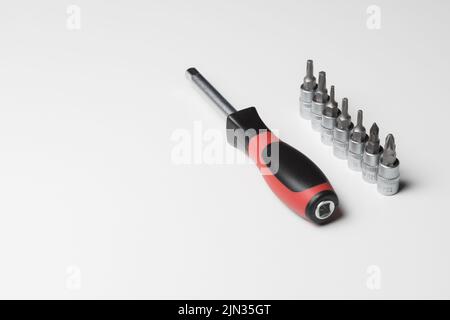 Manual screwdriver with attachments on a white table. A set of attachments for a manual screwdriver. Repair concept Stock Photo