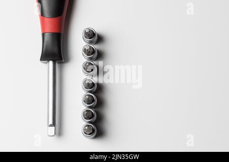 Screwdriver with attachments on the table on a white background. A set of small nozzles. View from above Stock Photo