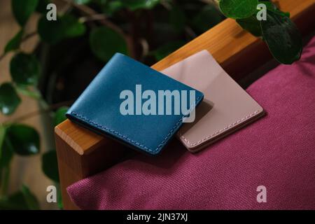 Two colored genuine leather wallets lying on a purple sofa indoors Stock Photo