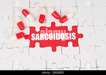 Medical concept. There are pills on the white puzzles, in the middle there is a red surface with the inscription - Sarcoidosis Stock Photo