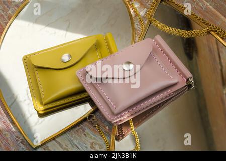 Beautiful modern women's leather wallets lying on mirrors on a sunny day Stock Photo