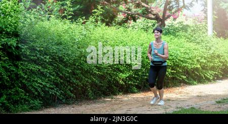 Mature woman running in the park in summer morning Stock Photo
